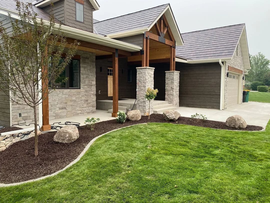 Modern home exterior with stone accents, landscaped yard, and decorative boulders.