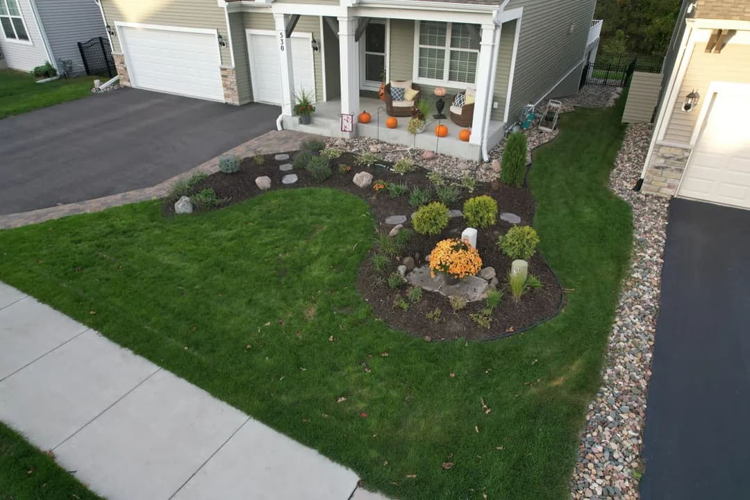 Landscape design featuring a pumpkin-decorated front yard with decorative bushes and stones.