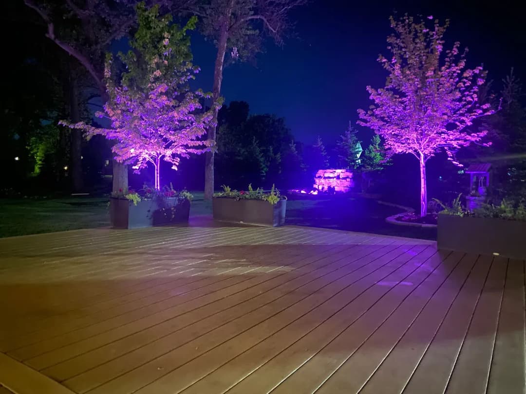Serene outdoor setting at night with illuminated trees and a wooden deck.