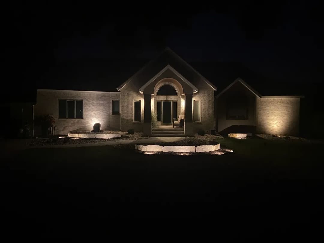 Illuminated modern home exterior at night with landscaped lighting and inviting entrance.