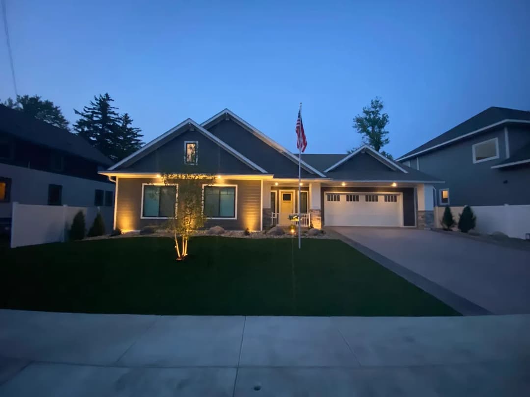 Modern home exterior at dusk with landscaping and American flag displayed.