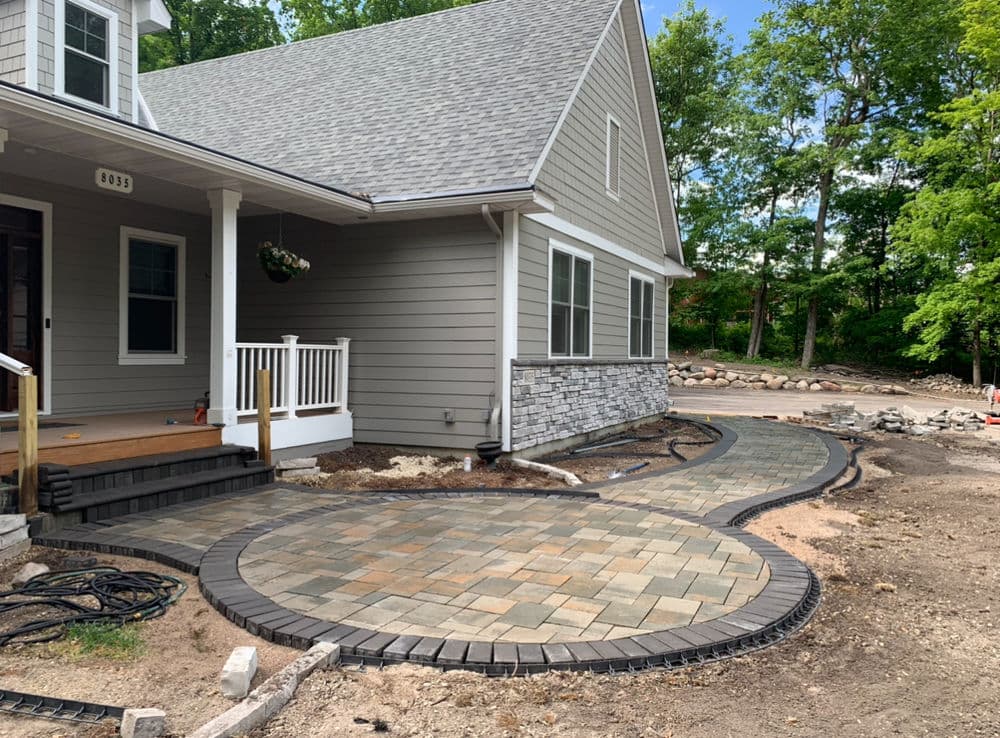 Modern home exterior with newly paved walkway and stone accents in landscaped surroundings.