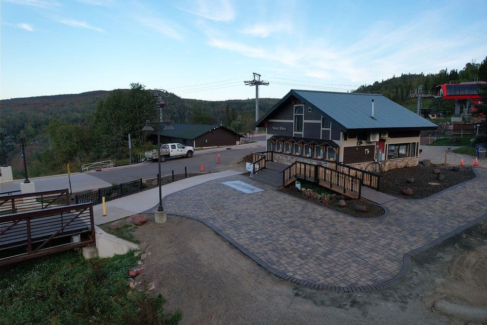 Mountain lodge with paved entrance near ski lifts and scenic hillside view.