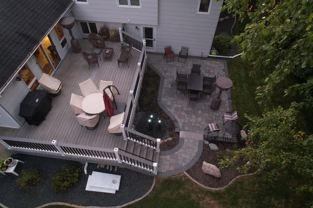 Aerial view of a deck and patio with outdoor furniture, grill, and landscaped walkway.