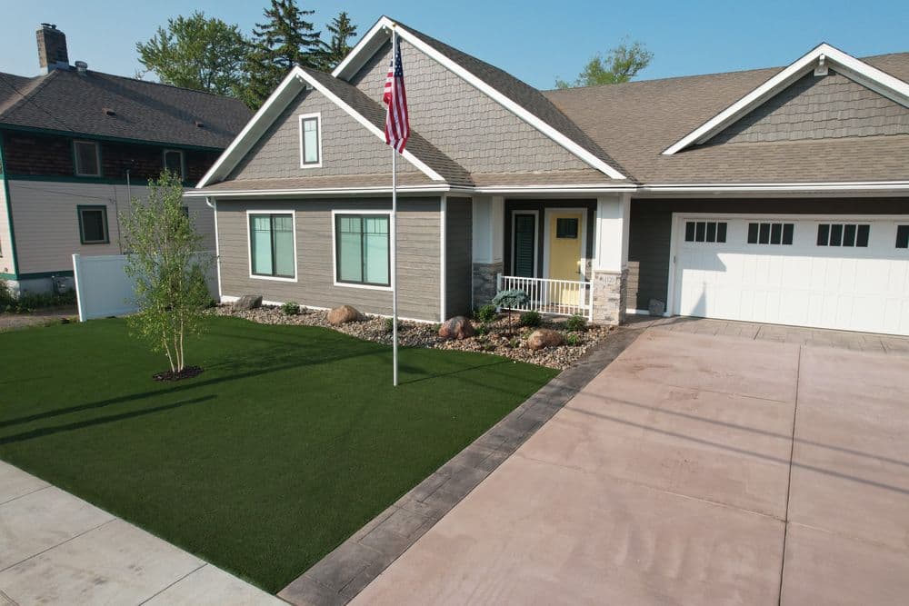 Modern home exterior with American flag, manicured lawn, and driveway.