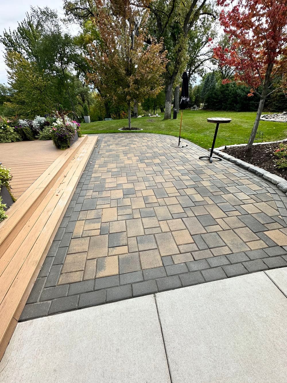 Paved pathway with interlocking stones, surrounded by greenery and autumn trees.