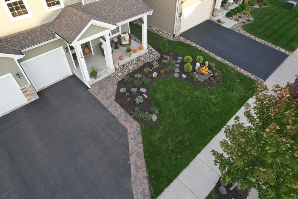 Aerial view of a well-landscaped driveway with a garden and autumn decorations.